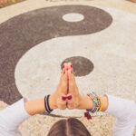 A woman meditating over a chalk yin and yang symbol.