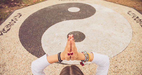 A woman meditating over a chalk yin and yang symbol.