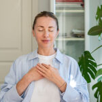 A woman meditating with her hands over her heart.