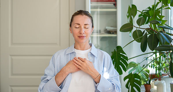 A woman meditating with her hands over her heart.