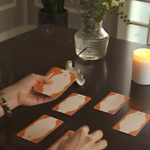 An image of a woman sitting by a table, laying out a psychic development Tarot spread.
