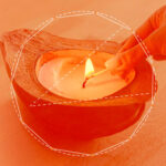 An orange-tinted image of an elemental attunement ritual, showing someone lighting a candle in a stone bowl with a match.
