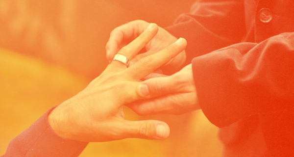 An orange-tinted marriage tarot cards header image of some putting a ring on their partner's hand.