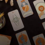 An image of a dream interpretation Tarot spread. It is laid out in a diamond-pattern on a mahogany table.
