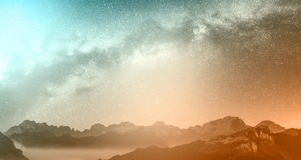 An image of a mountainous horizon, tinted orange, while teal blue clouds float in the sky above.