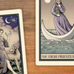 An image of three cards on a table. To the left is a card depicting a woman with a staff. The name of the card is not visible. In the center is the High Priestess, depicted as a woman on a small boat. The card on the far right is cut off, with only the border visible.
