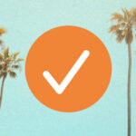 An image of an orange checkmark. The background is of a teal sky with palm trees.