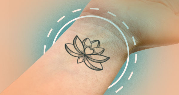 An image of a black outline lotus flower tattoo on the inside of someone's wrist.