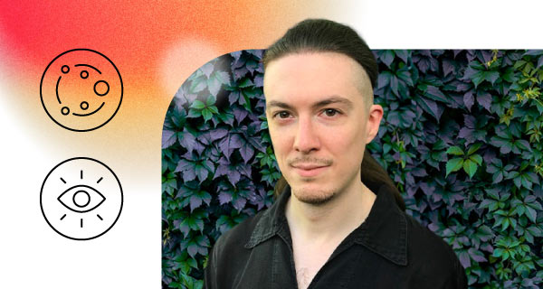 An image of Psychic Tobias, a young man with long brown hair, standing in front of a plant hedge.