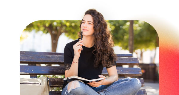 A woman sitting on a park bench with a journal in her lap.