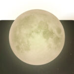 A moon tinted pale yellow against a dark sky,