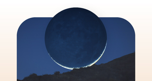 A dark silhouette of a moon over a hill.