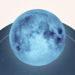 A blue tinted moon, the Cold Moon, rising over the night sky.