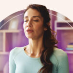 A woman meditating with an indigo aura emanating out from her.