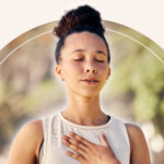 A woman meditating with a white aura emanating from around her.