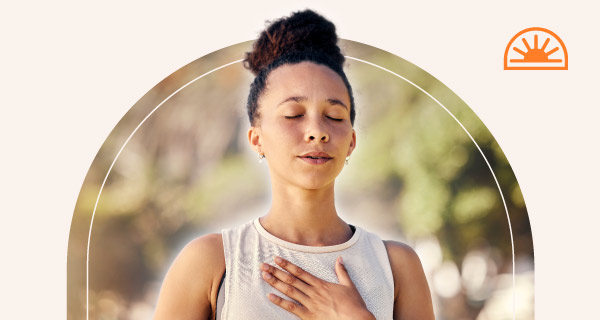 A woman meditating with a white aura emanating from around her.