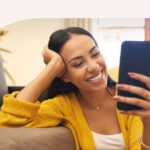 A woman smiling excitedly at her phone.