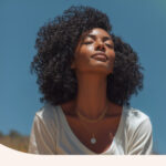 A woman outside meditating in the sun.