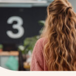A woman standing in front of a blackboard with the number 3 written across it.