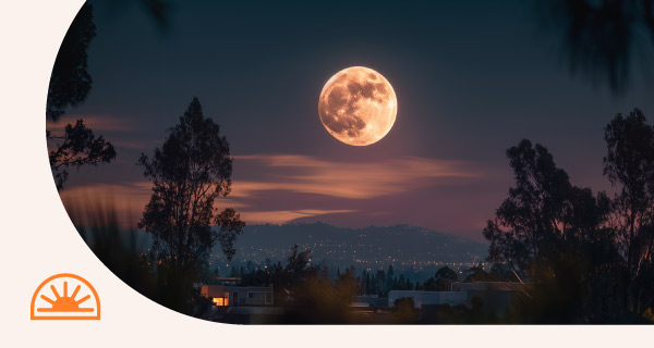 A micromoon rising in the sky over a cityscape.