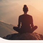 A woman sitting outside, meditating in the sunset.