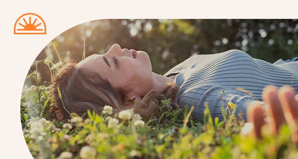 A person sleeping outside in a field of clover.