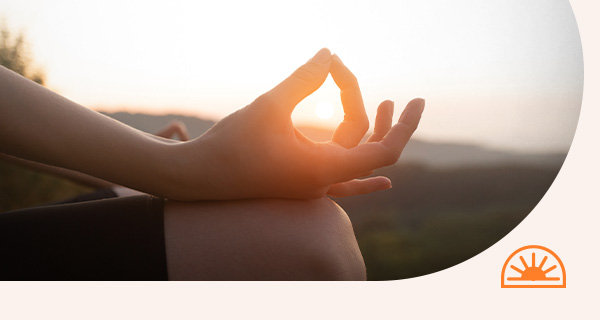 A person meditating in the sunset.