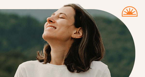 A woman outside with her head tilted to the sky.
