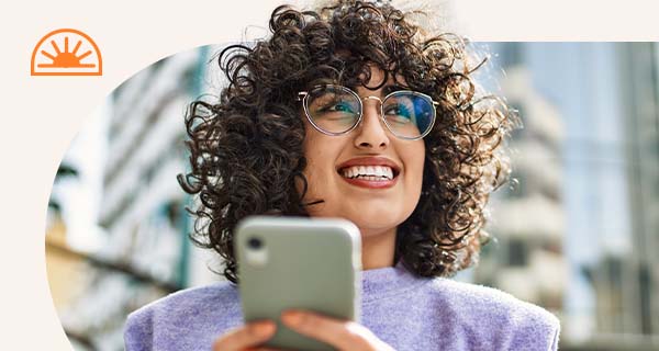 A woman in a purple shirt looks up from her phone, smiling.